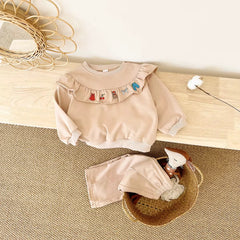 Children's beige outfit with ruffled collar.